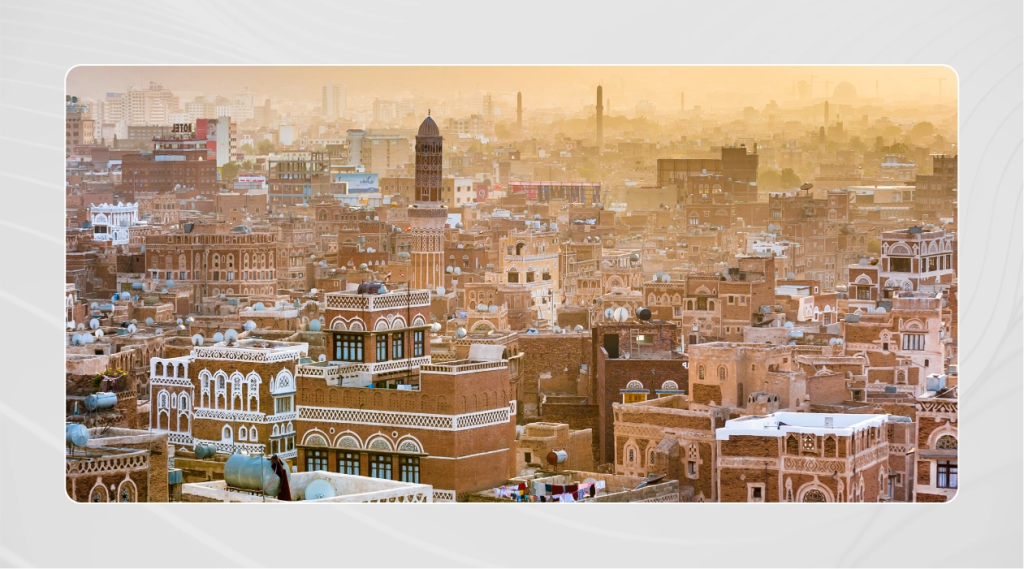 A wide view of Old City in Yemen, showing historical buildings built on top of a mountain and bright white frames onthe buildings.